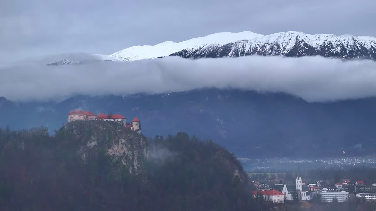 Una ripresa panoramica aerea del Castello di Bled con le montagne sullo sfondo.
