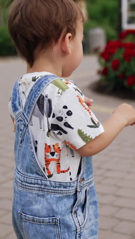 sweet baby boy in jeans romper. cute child playing with soap bubbles. walk in the park. vertical video