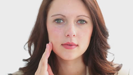 serious brunette massaging her cheek