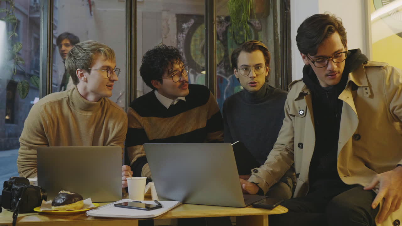 Freelancers talking about project in coffee shop. Professionals using laptop