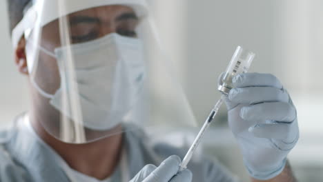 Doctor-in-Protective-Uniform-Drawing-Vaccine-out-with-Syringe