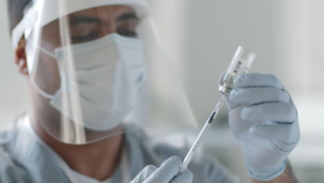médico en uniforme de protección sacando la vacuna con una jeringa