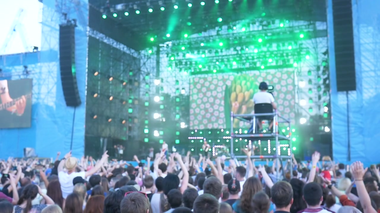 Large Crowd Cheering and Raising Hands at an Outdoor Music Concert
