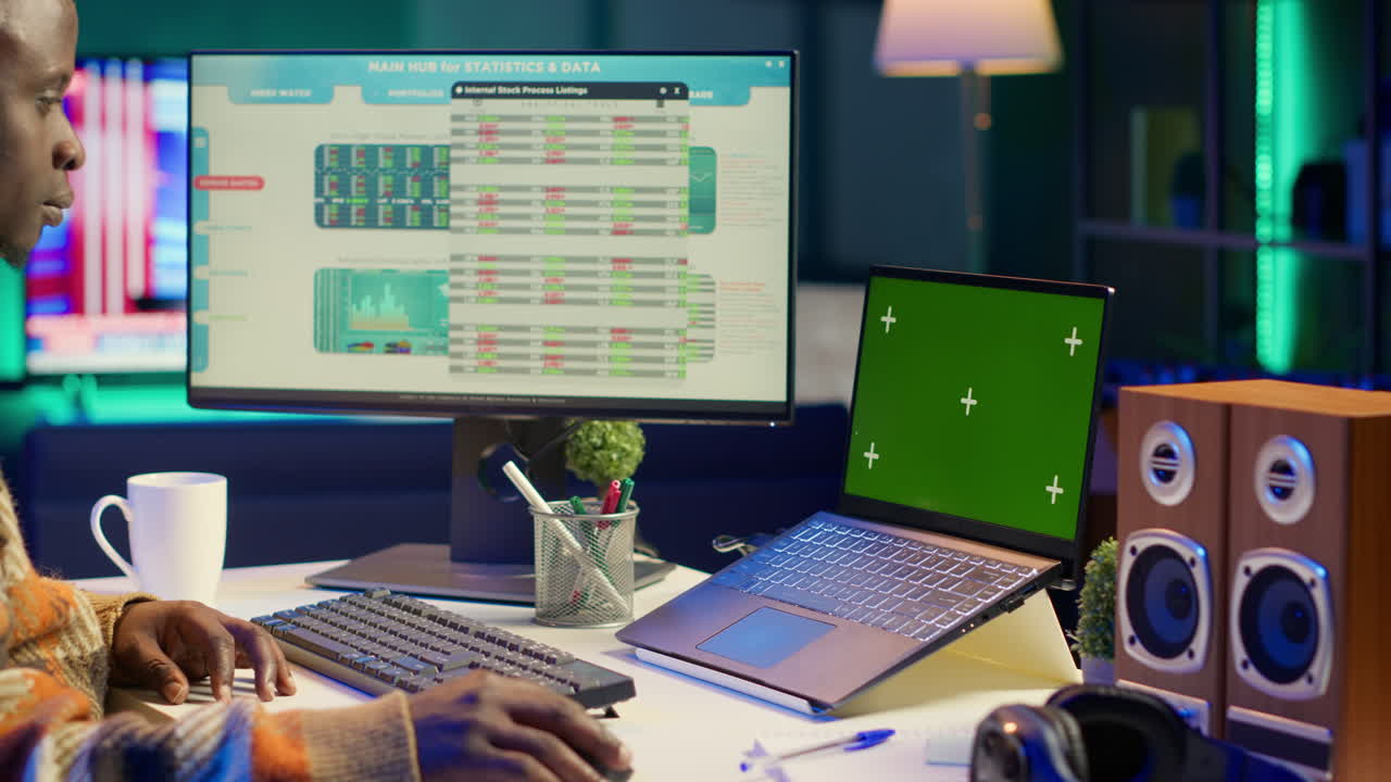 Workspace setup with green screen laptop, monitor, and peripherals