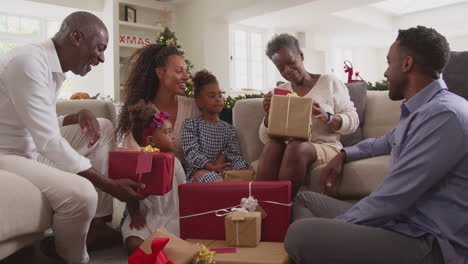 multi-generation family celebrating christmas at home opening presents together