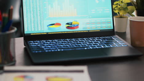 financial report on desk next to laptop showing marketing statistics in office