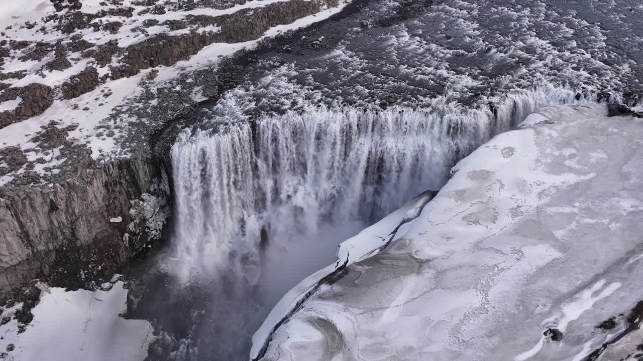 Icy cliffs and powerful water plunge at Dettifoss waterfall in Iceland's frozen wilderness