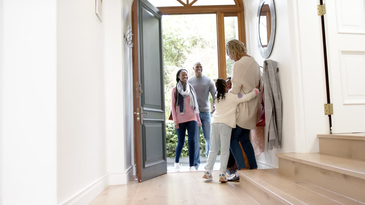 행복한 아프리카계 미국인 할머니가 집에서 손녀와 그녀의 부모를 환영합니다.
