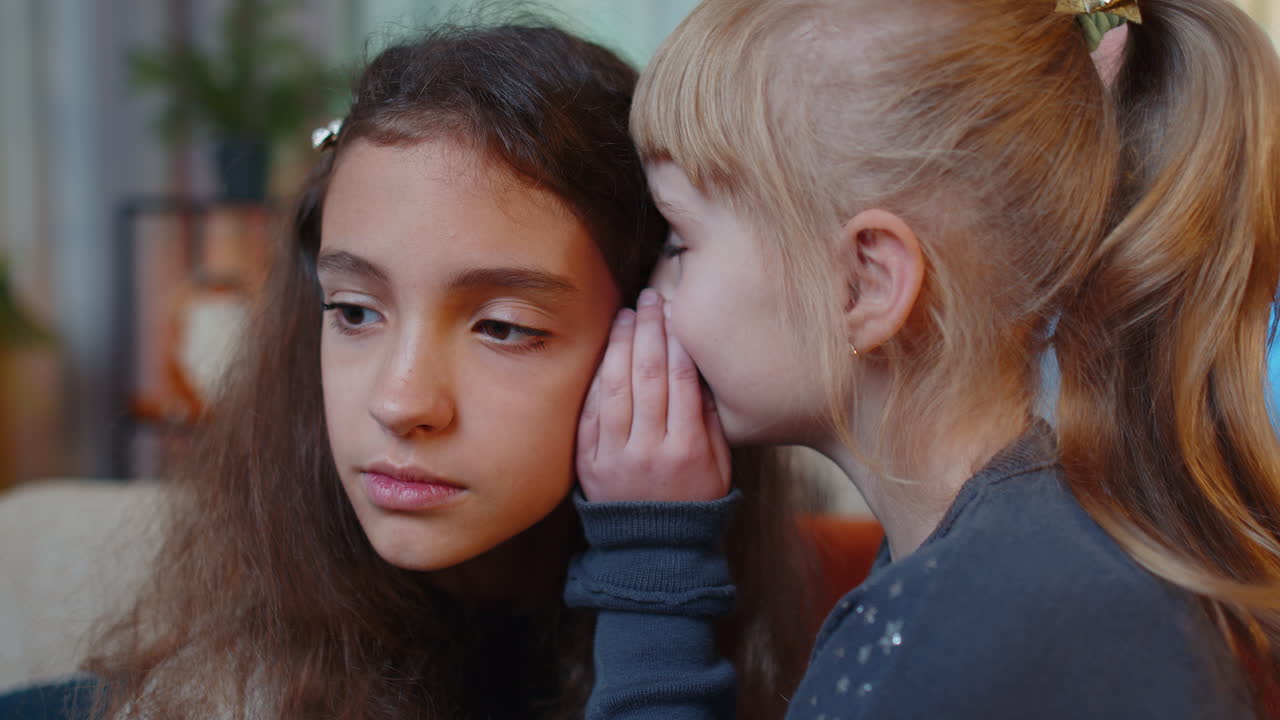 niño adolescente susurro noticias rumores en el oído a la hermana pequeña niña compartir secretos chismes divirtiéndose