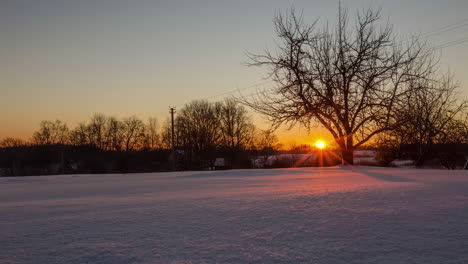 un amanecer naranja y brillante sobre un invierno, un prado rural cubierto de nieve fresca - lapso de tiempo
