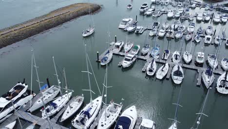 aerial view tracking boat leaving wealthy yacht marina navigating luxury expensive sailboat waterfront