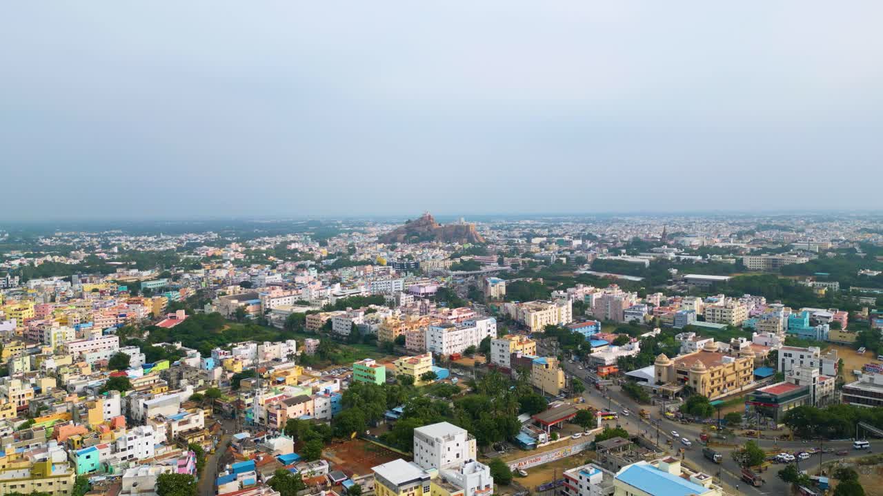 el paisaje urbano indio densamente poblado de tiruchirappalli con arquitectura diversa al anochecer y el fuerte de roca de malaikottai en el fondo