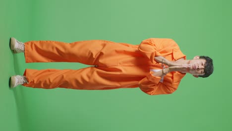 full body of asian male prisoner in handcuffs standing on the green screen background, making pray hand gesture asking for something
