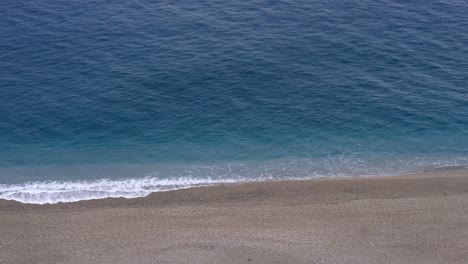 Leerer-Sandstrand-Mit-Welligem-Blauem-Wasser