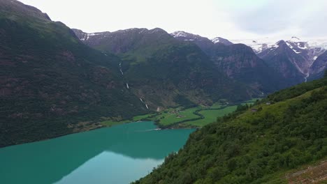 Approaching-Indre-Yrisetra-mountain-cottage-above-Oldevatn-lake-in-Olden-Norway---Stunning-aerial-with-unique-perspective-and-the-Briksdal-glacier-in-background