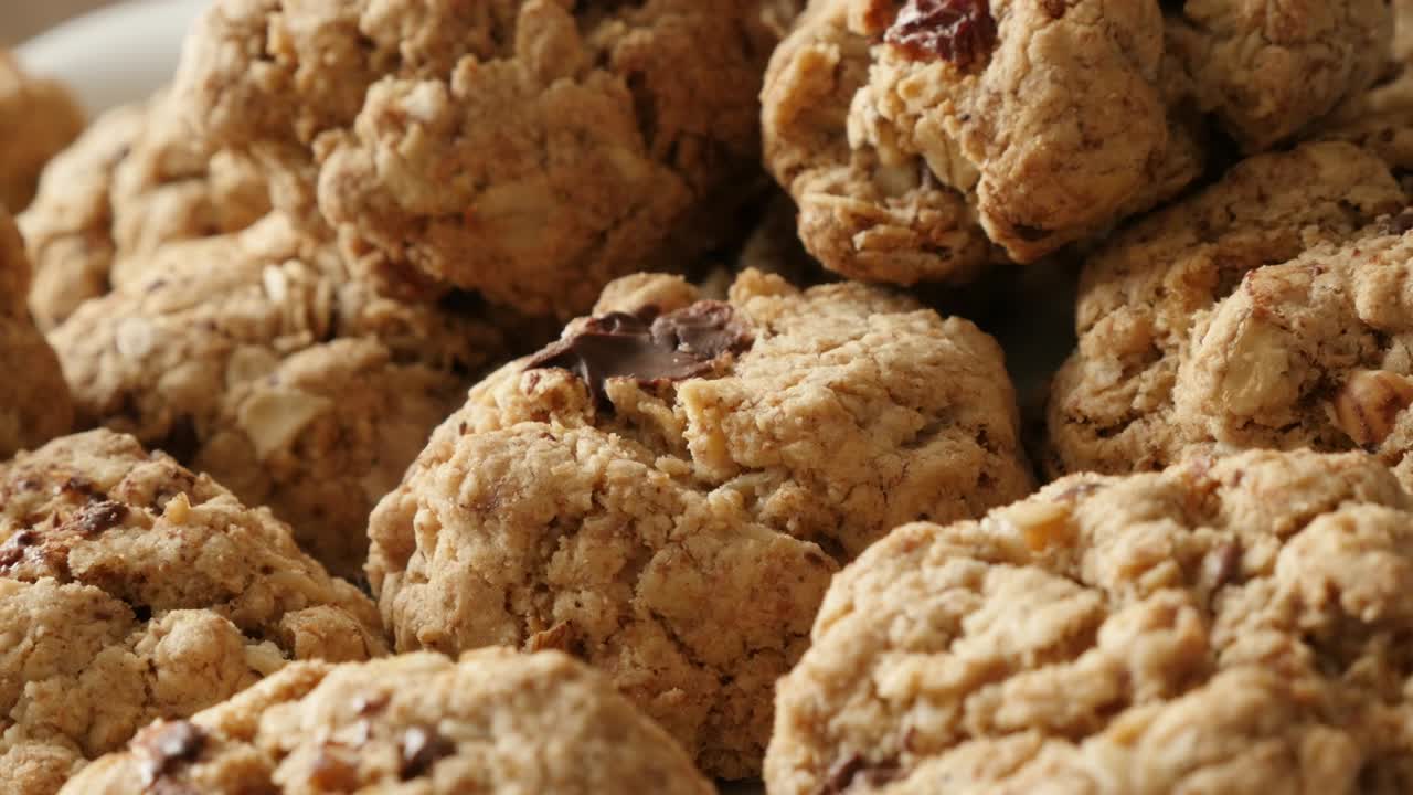 Biscotti d'avena con profondità di campo ridotta serviti su un piatto. Filmato panoramico UHD 4K 2160p 30fps. Pila di biscotti fatti in casa con gocce di cioccolato, panoramica lenta ravvicinata. Video UltraHD 3840x2160.