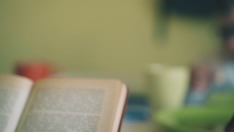 niño lee el libro de texto cerca de su compañero de clase comiendo el almuerzo en la mesa