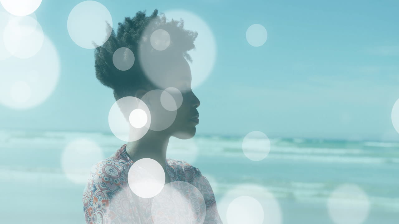 woman gazing toward horizon on beach, showing health data charts with bokeh overlays
