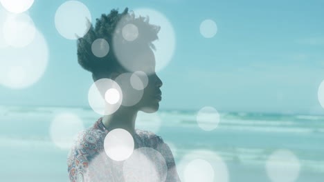woman gazing toward horizon on beach, showing health data charts with bokeh overlays