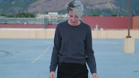 Caucasian-white-girl-in-empty-parking-lot-throwing-hands-down-punching-the-air-as-she-has-mental-breakdown-with-mountains-and-building-in-background