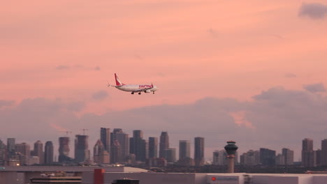 an xxx aircraftflies descends across the city skyline before landing on a runway at pearson international