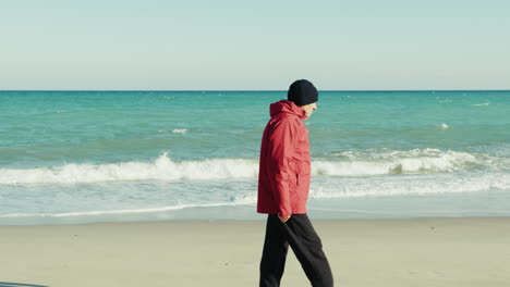 elderly man in a jacket walks calmly by the sea