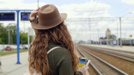 girl with coffee and mobile phone waiting for the train