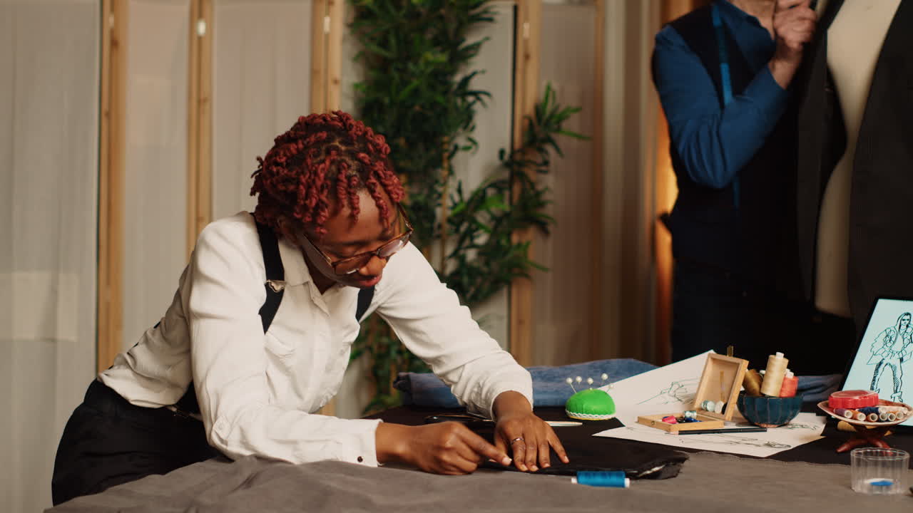Apprentice measuring fabric in atelier