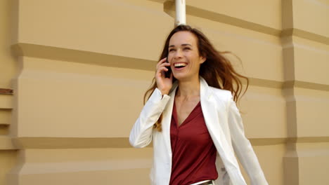 Happy-businesswoman-walking-with-mobile-phone-outdoors