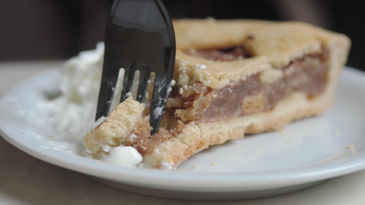 Slow Motion Close-up of a Fork Cutting a Piece of Apple Pie with Whipped Cream