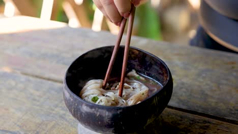 person eating noodles with chopsticks in bangkok