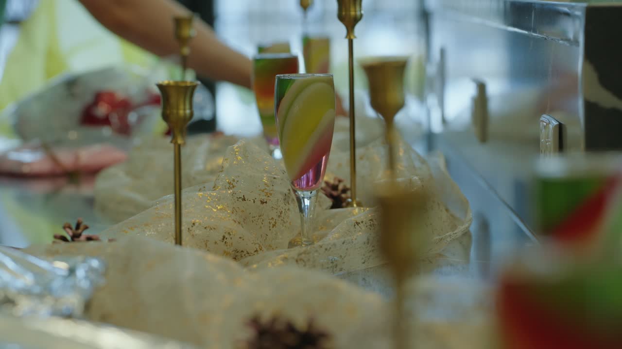An elegant table setting featuring multi-hued dessert flutes, gold candlesticks, and shimmering fabrics, capturing a festive ambiance for special gatherings.