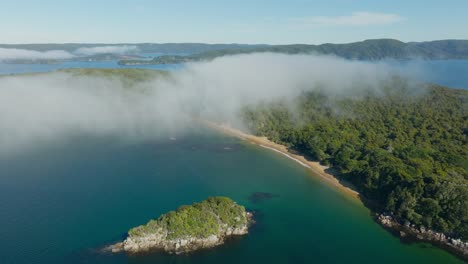 Aerial-view-flying-toward-remote-sandy-beach-with-calm-placid-ocean-at-Ulva-Island-within-Paterson-Inlet,-Stewart-Island-Rakiura-in-the-south-of-New-Zealand-Aotearoa