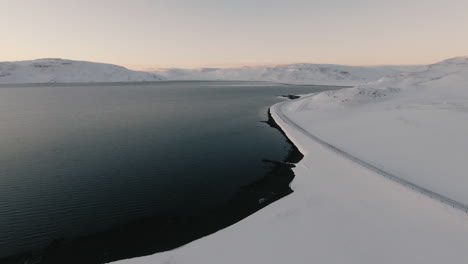 ocean shore, winter road and snowy mountain landscape from above