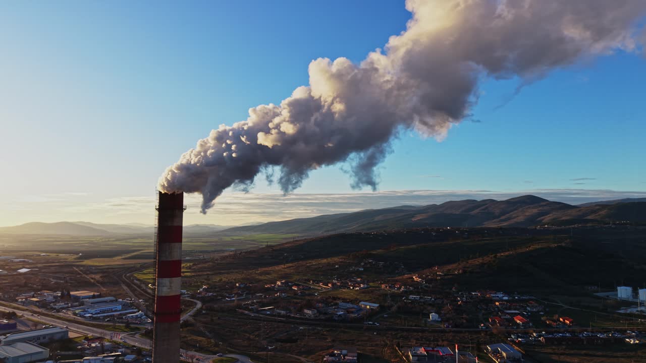Smoke rises from a chimney in a rural area during the day
