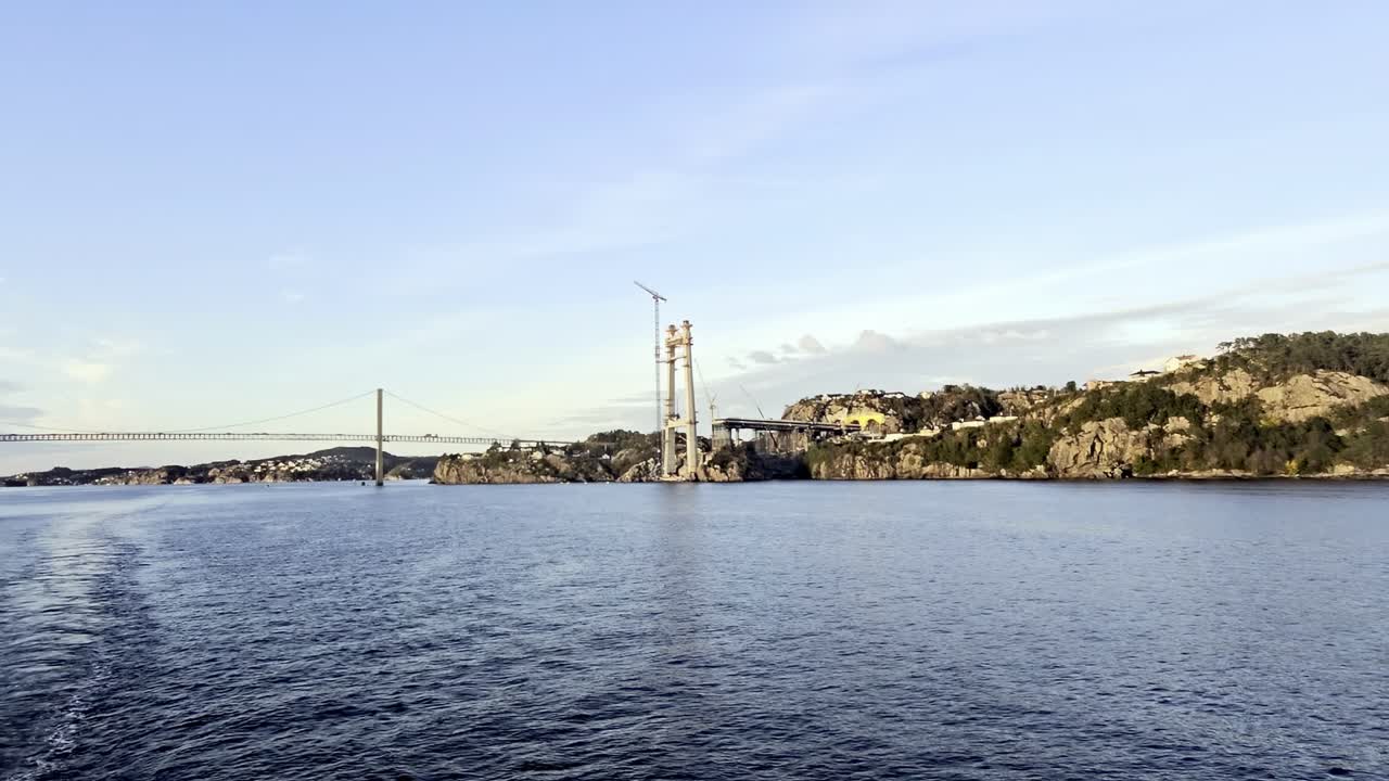 Evening view from sea showing wake toward new Sotra Bridge tower and old bridge with traffic
