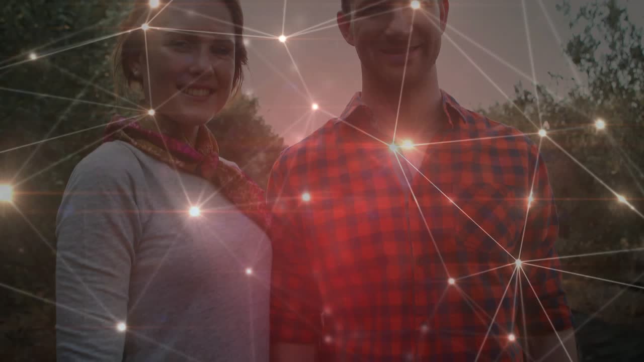 Couple standing in grove at sunset receiving pulsing network overlay highlighting connection fading