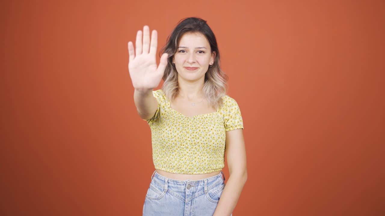 mujer joven haciendo una señal de alto para la cámara.