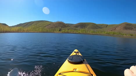 first-person kayaking on a scenic lake surrounded by green hills