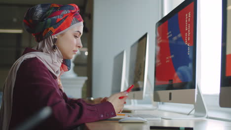 muslim businesswoman using smartphone and computer at work