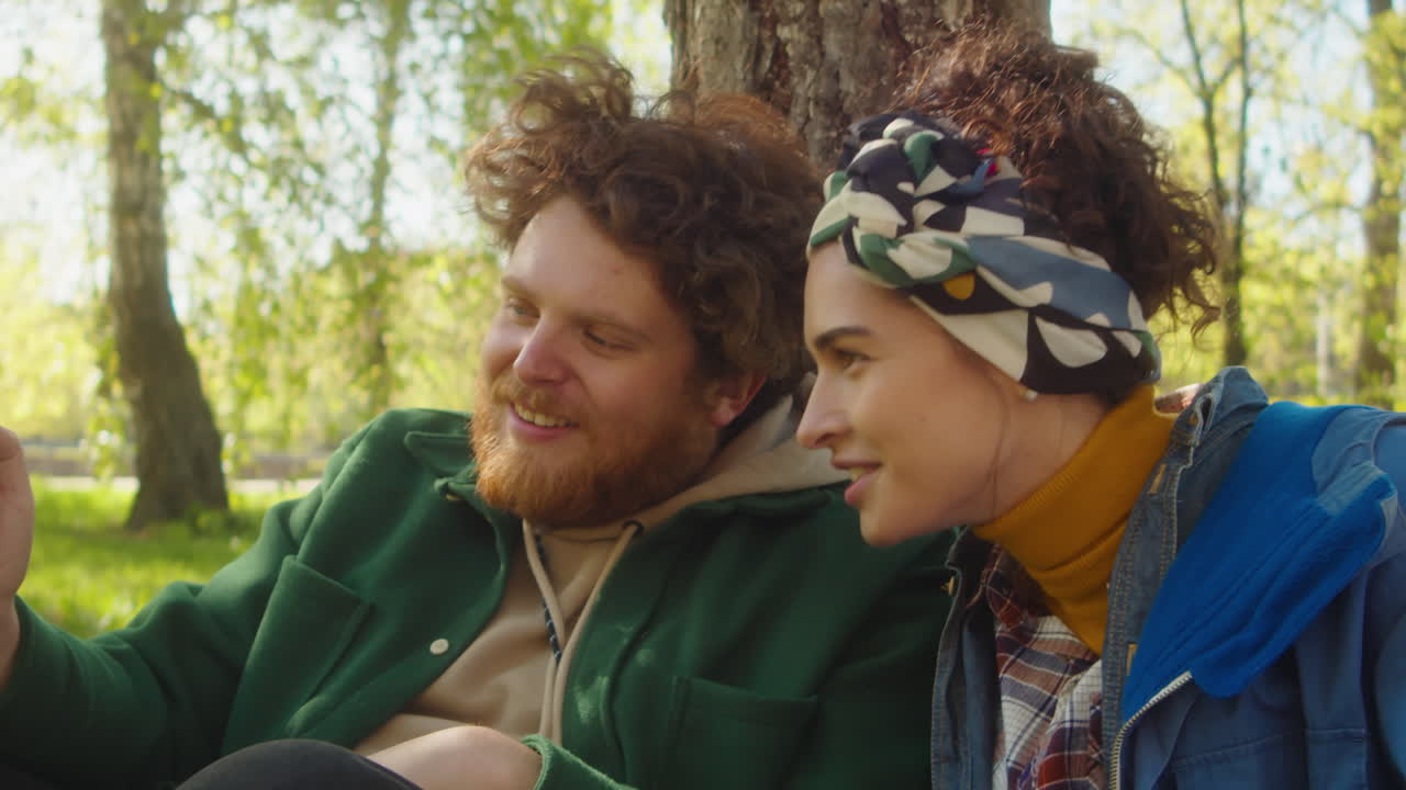 A happy couple or friends relaxing and talking outdoors in a sunny park
