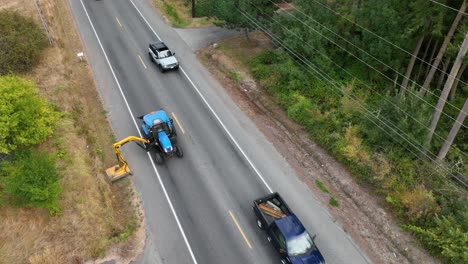 tiro de dron del tractor con un accesorio de cortacésped mientras conduce lentamente por la carretera para cortar las malas hierbas