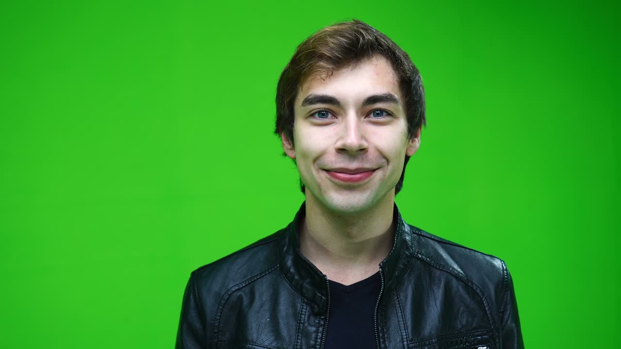 hombre blanco alegre en chaqueta de cuero mirando a la cámara y sonriendo sobre el fondo de la pantalla verde.