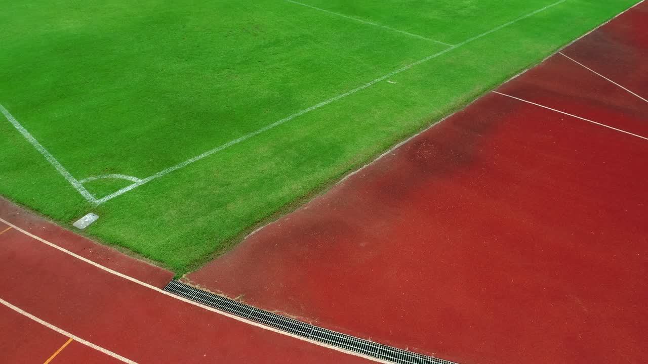 Löparbana och hörna på fotbollsstadion, färgen är tegelröd, högvinkelvy med drönare.