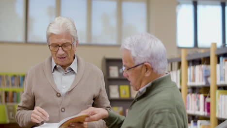 elderly caucasian men discussing book in library