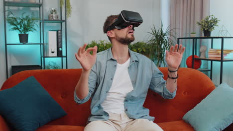 Man-using-virtual-reality-futuristic-technology-headset-to-play-simulation-3D-video-game-at-home