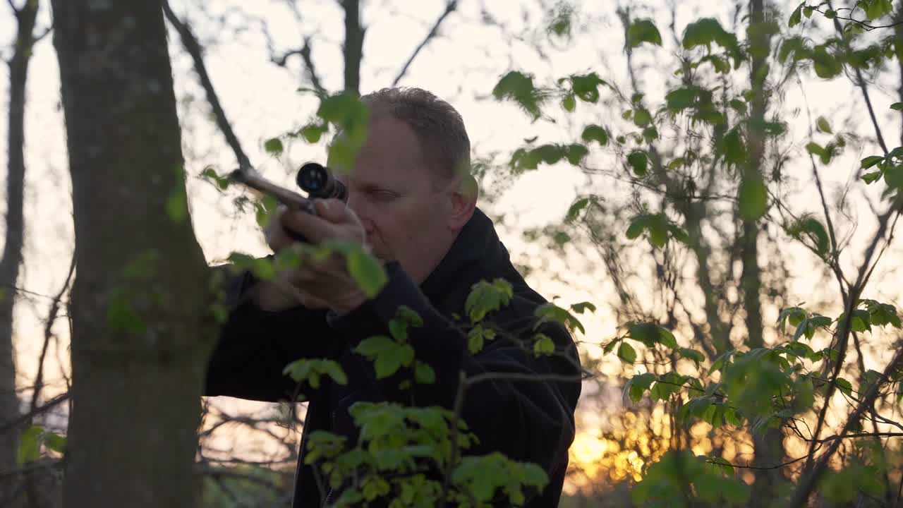 Male hunter aiming through trees ready to take the shot
