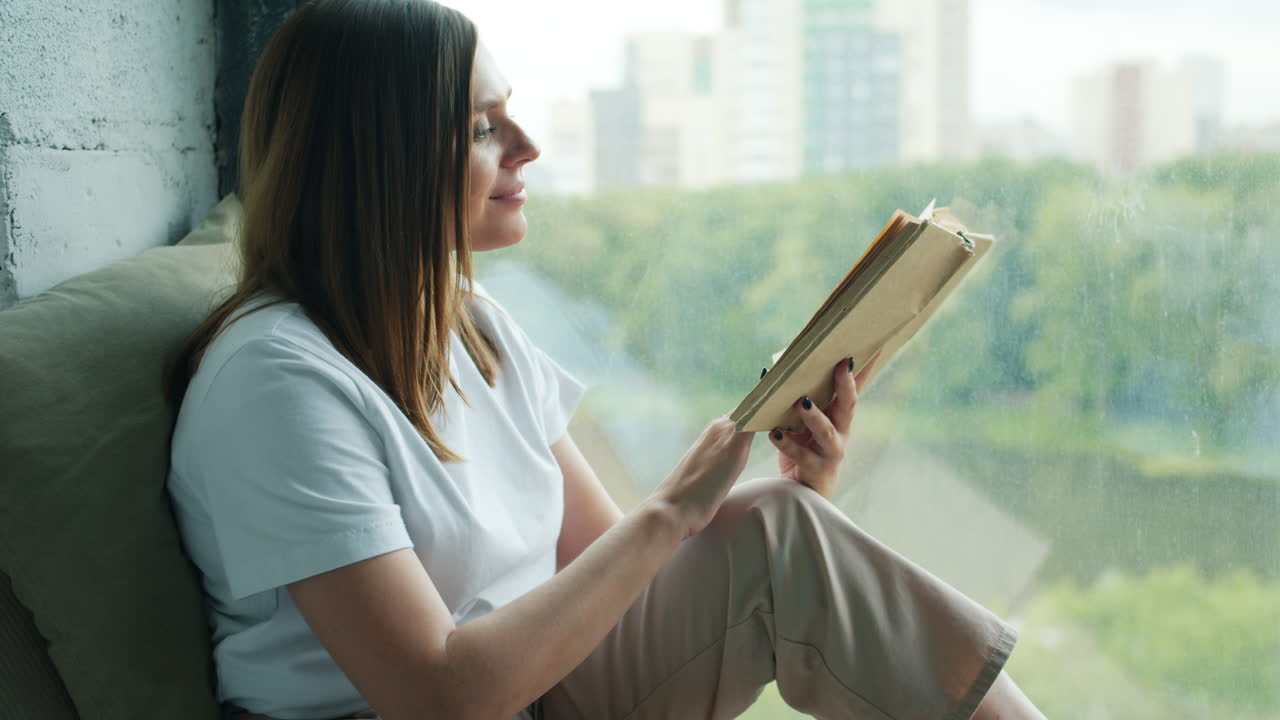mujer leyendo un libro junto a la ventana