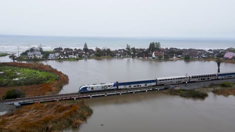 Vista-Aérea-Del-Tren-Costero-Que-Pasa-Sobre-Una-Laguna