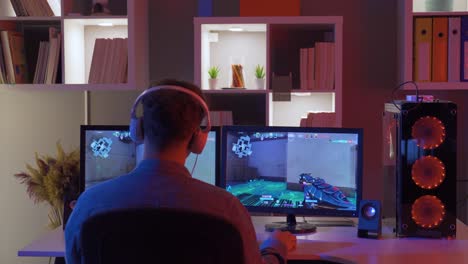 young boy playing a game sitting in front of a computer, wearing headphones.